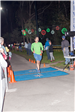 Man in Blue Shorts and Green Shirt Running Across a Finish Line